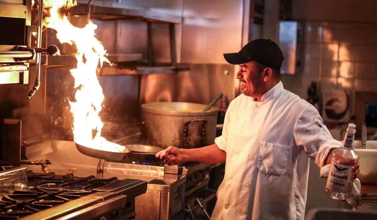 A professional chef searing food in a kitchen