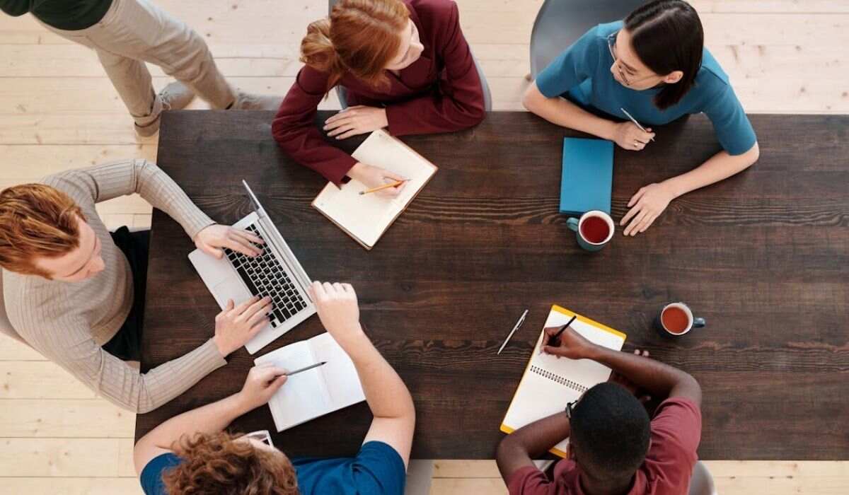 people discussing office work in a meeting with some documents on table and coffee cups