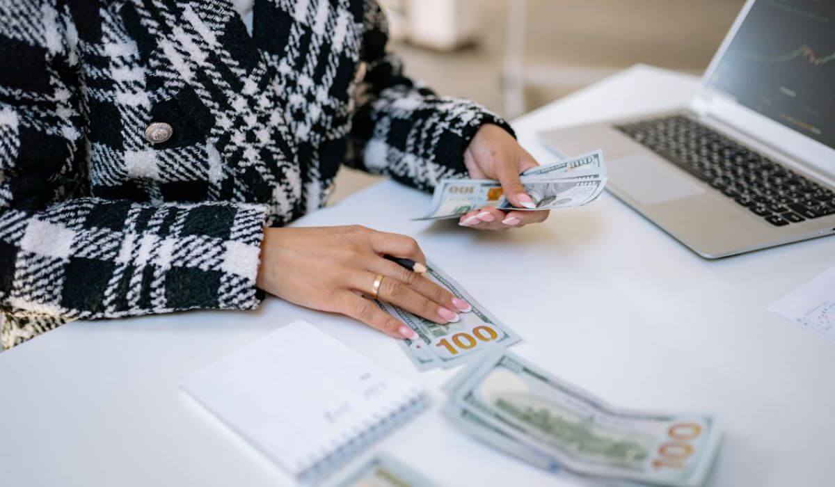 A women owning a small business, handling cash with a laptop placed on the table