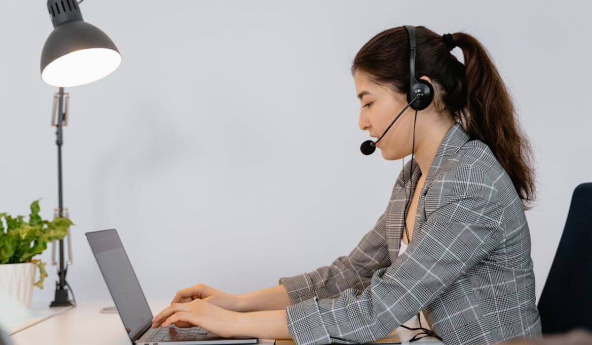 Virtual Assistant working on a laptop wearing headphones with a mic