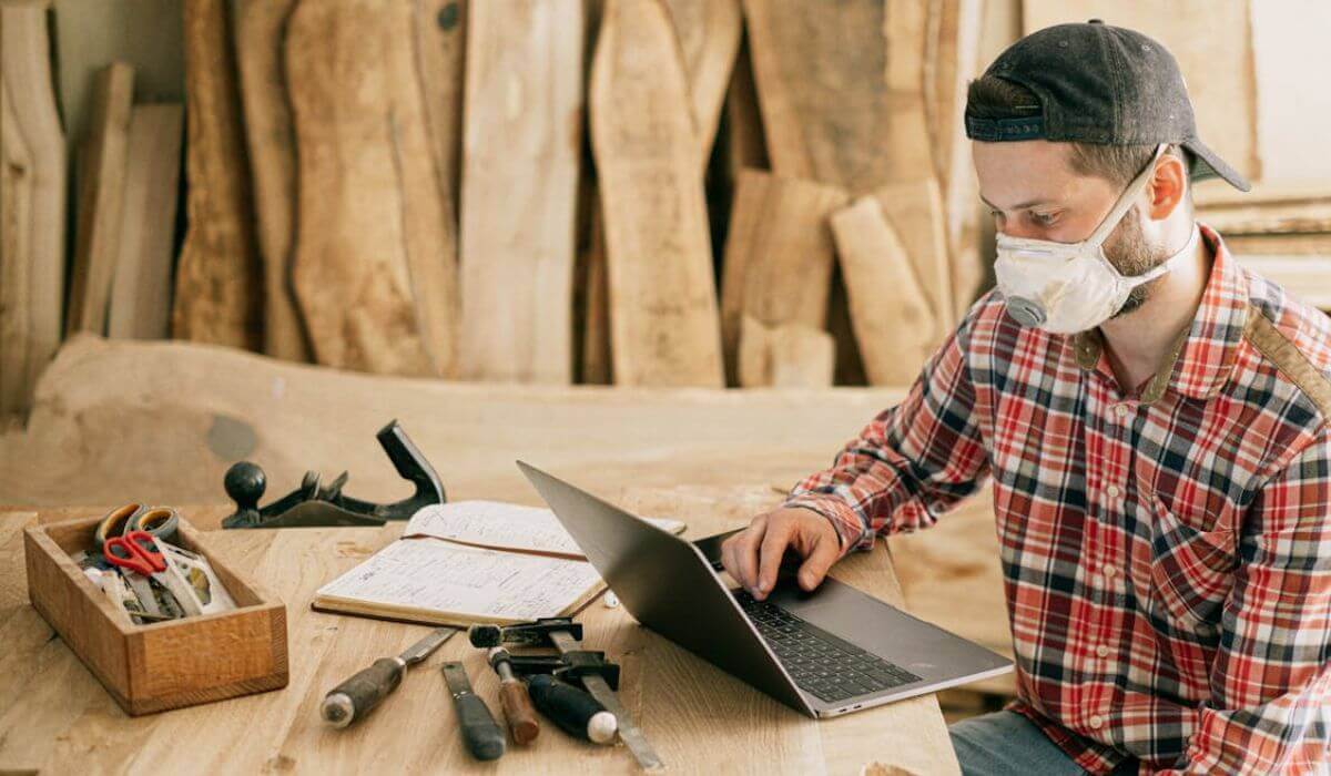 handyman typing on a laptop with tools on scattered on the table