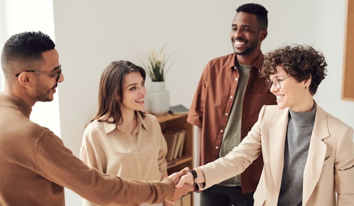 An employee smiling at its employer while the female boss shakes hand with its employee