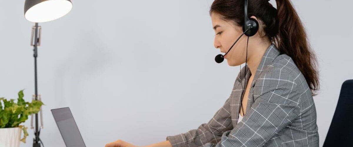 Virtual Assistant working on a laptop wearing headphones with a mic